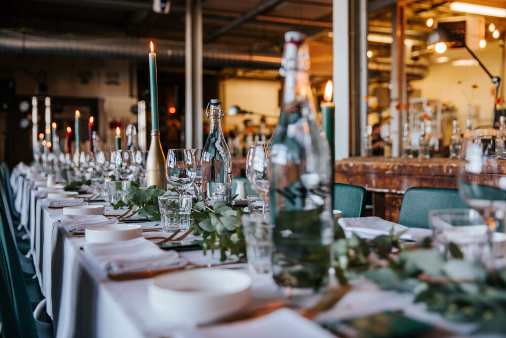 Mike+Sophie-305 Lange gedekte tafel met kaarsen en groen voor een bruiloftsdiner